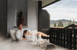 Pärchen im Bademantel auf dem Balkon des Ludwig Royal im Allgäu mit Blick auf die Berge.