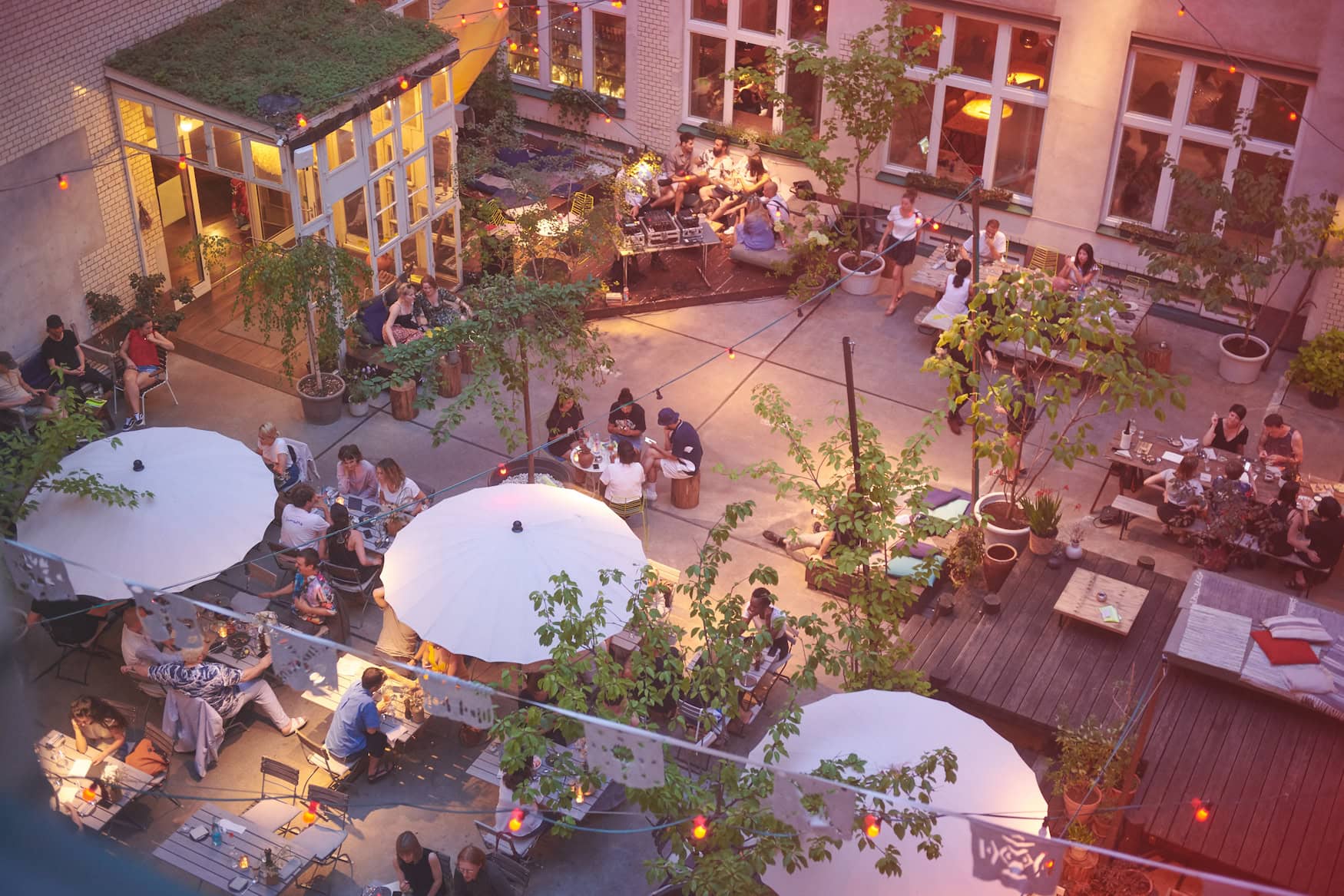 Begrünter Innenhof des Michelberger Hotels mit Lichterketten am Sommerabend, Berlin