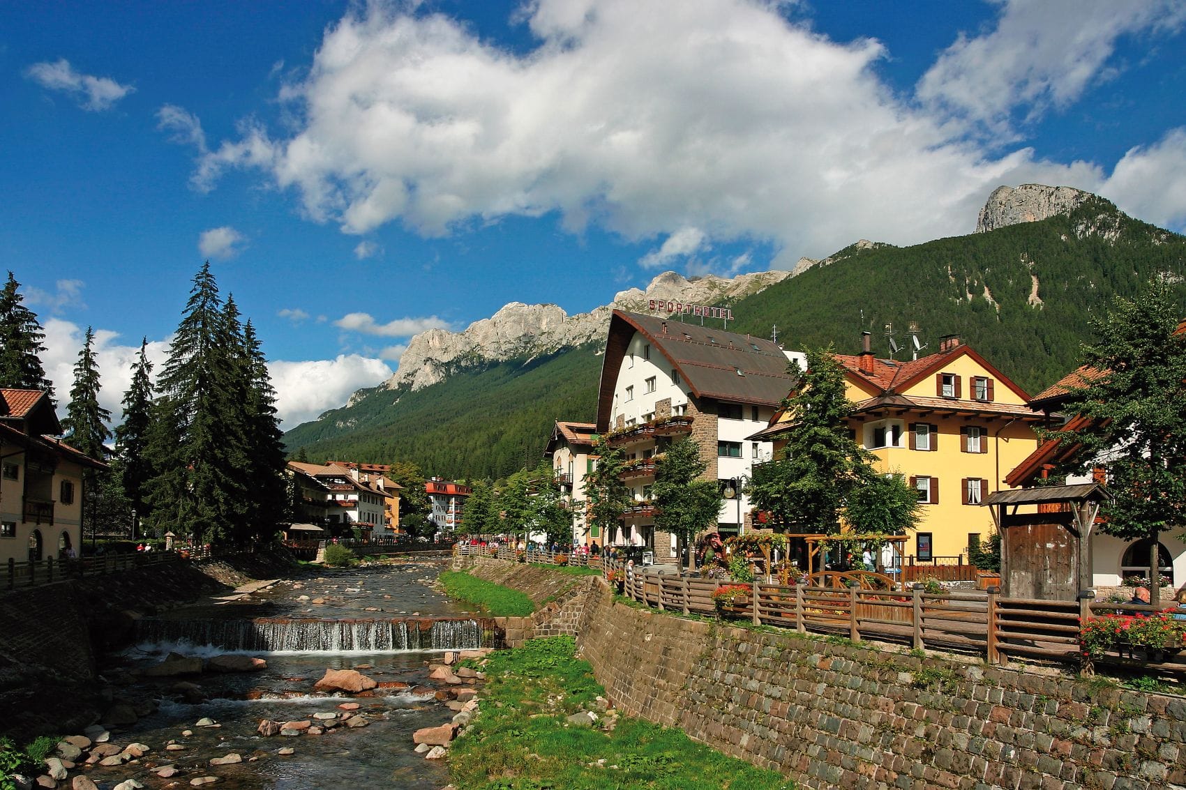 Blick auf Moena im Trentino mit dem Fluss Avisio und den Dolomiten im Hintergrund