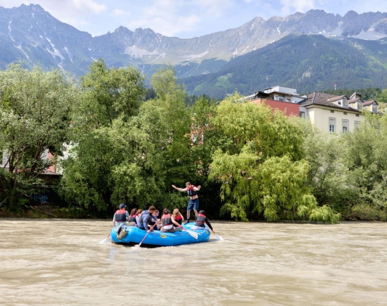 Teilnehmer einer geführten Rafting-Tour auf dem Inn vor der Kulisse der Innsbrucker Altstadt und der Nordkette in Tirol.