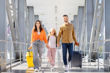 Familie mit Rollkoffern auf dem Weg zum Abflug im Flughafen-Terminal