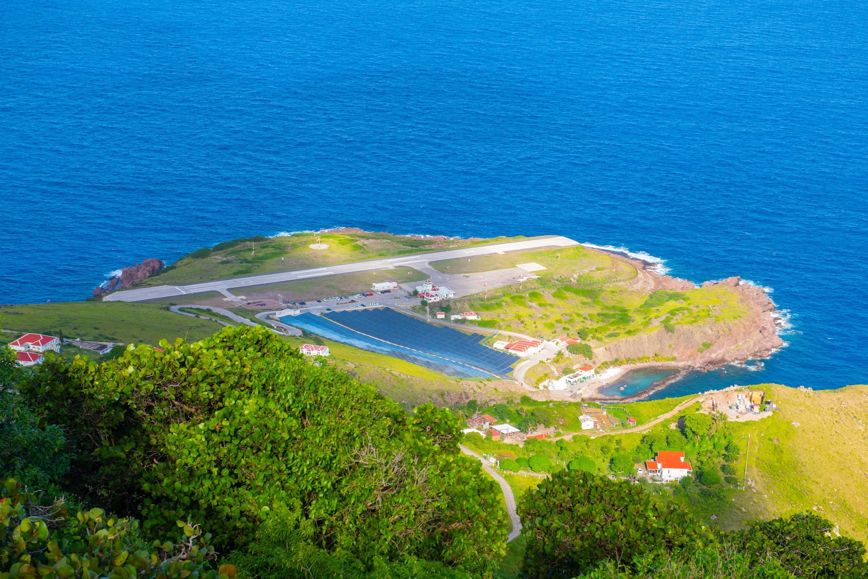Luftaufnahme der Juancho E. Yrausquin-Landebahn auf Saba, umgeben vom Atlantik auf einer Halbinsel aus grünen Hügeln