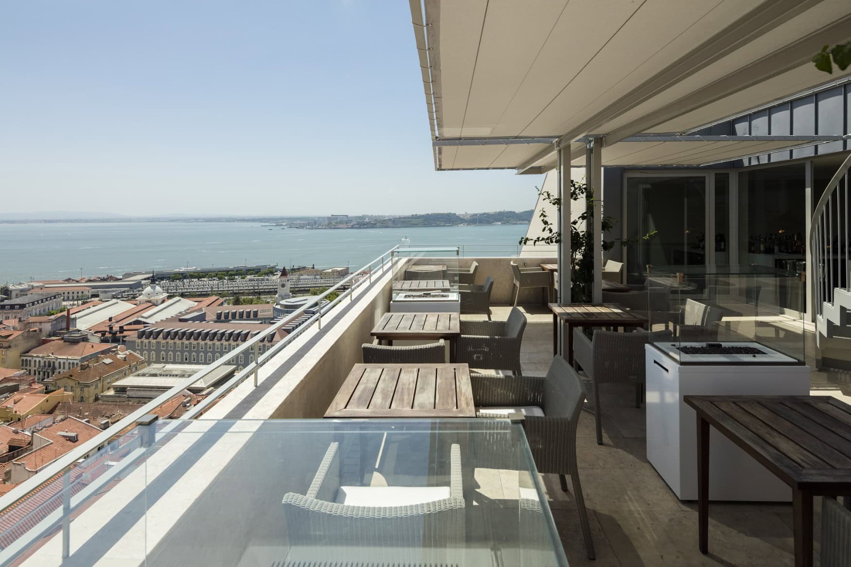 Terrasse des Restaurants Suba im Hotel Verride Palácio in Lissabon, mit Holztischen und Korbsesseln.