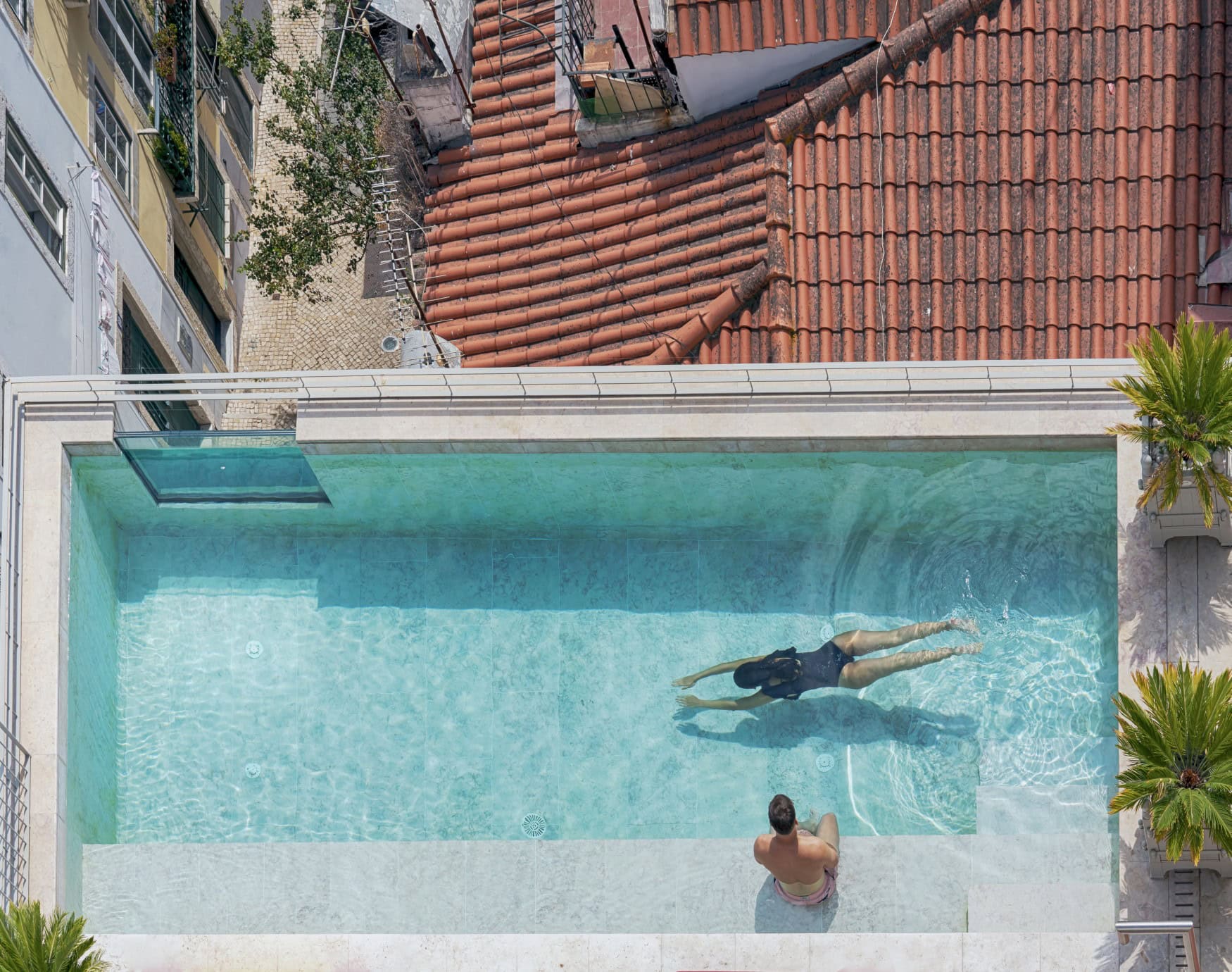 Drohnensicht auf einen kleinen, aber eleganten Rooftop-Pool über den Dächern Lissabons