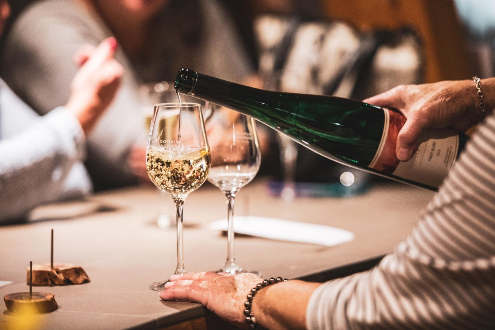 Bei einer Weinverkostung an der luxemburgischen Mosel schenkt eine Gastgeberin einen Crémant in ein Weinglas ein.