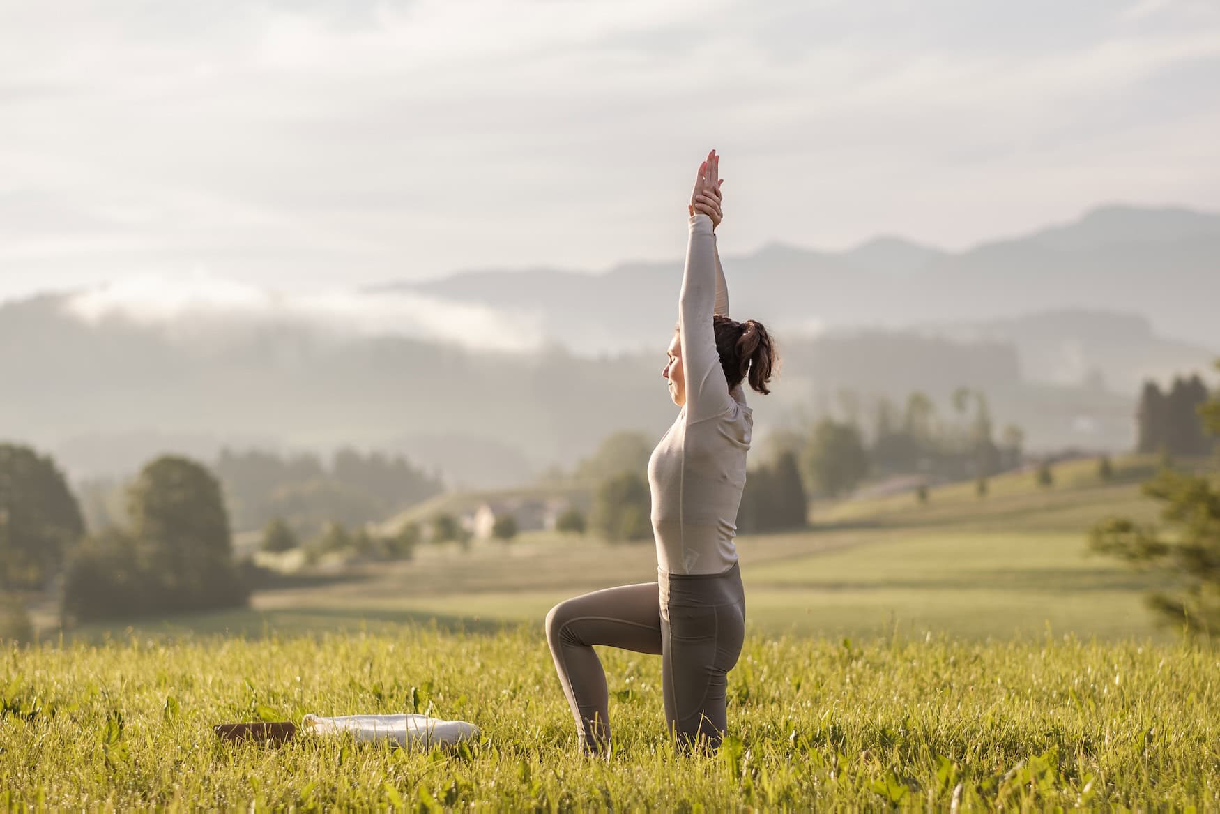 Eine Frau macht Yoga auf einer Wiese.