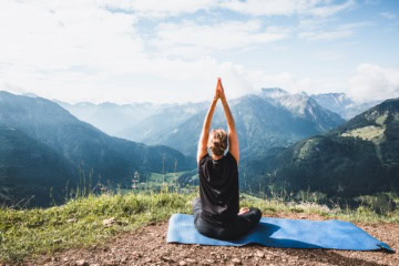 Eine Frau macht Yoga in den Bergen im Allgäu.