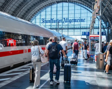 eisende mit Koffern gehen am Frankfurter Hauptbahnhof an einem ICE der Deutschen Bahn entlang.
