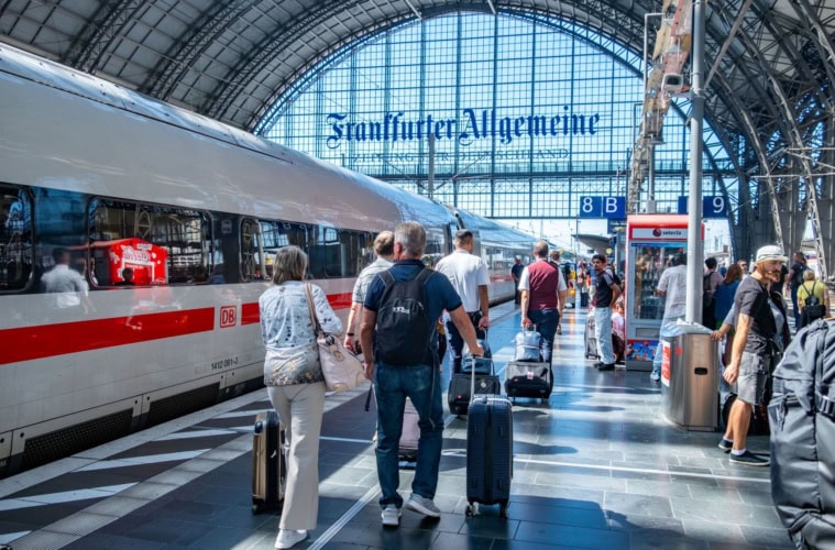 eisende mit Koffern gehen am Frankfurter Hauptbahnhof an einem ICE der Deutschen Bahn entlang.