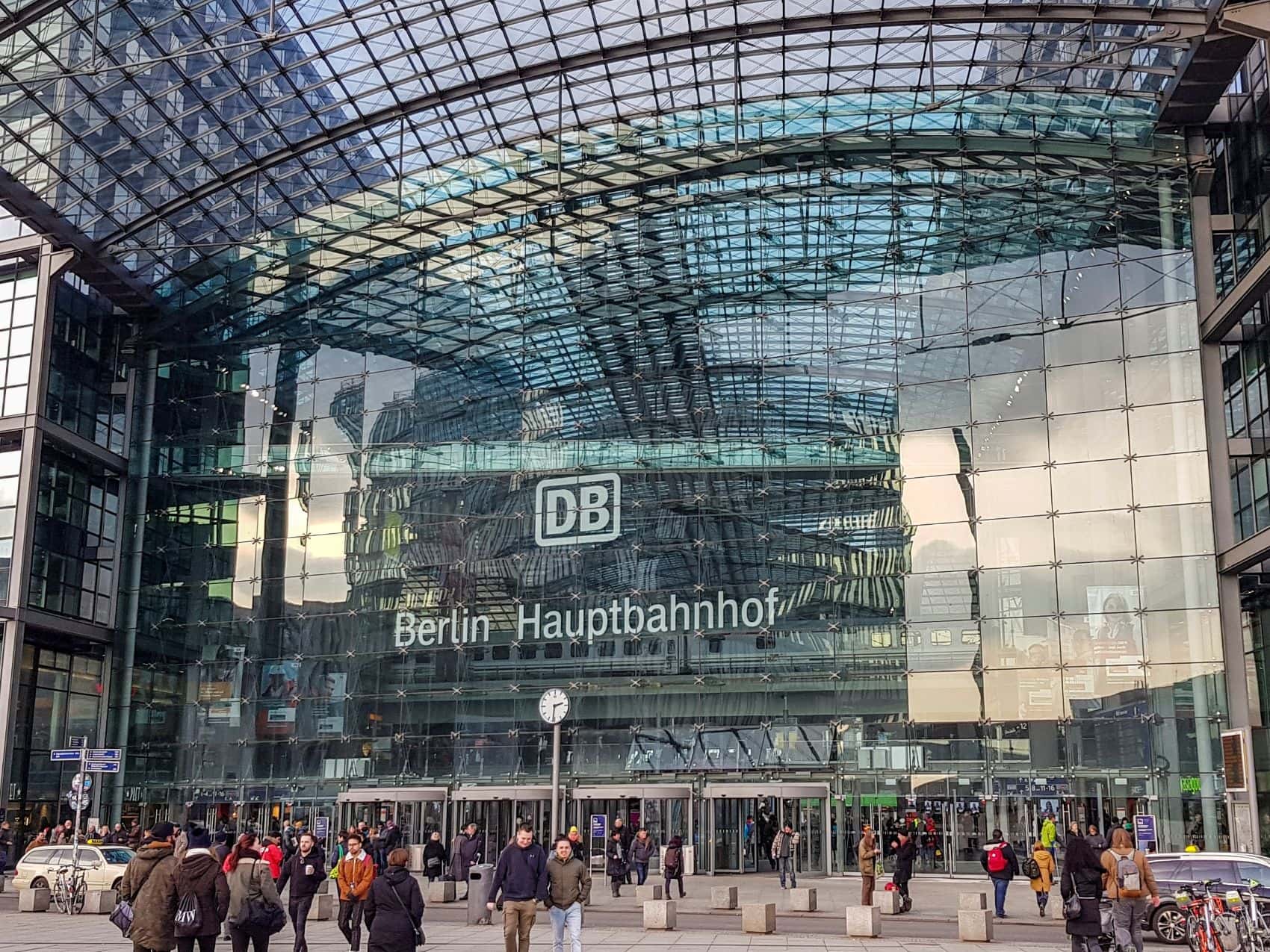 eisende vor dem Eingang des Berliner Hauptbahnhofs mit dem Logo der Deutschen Bahn.
