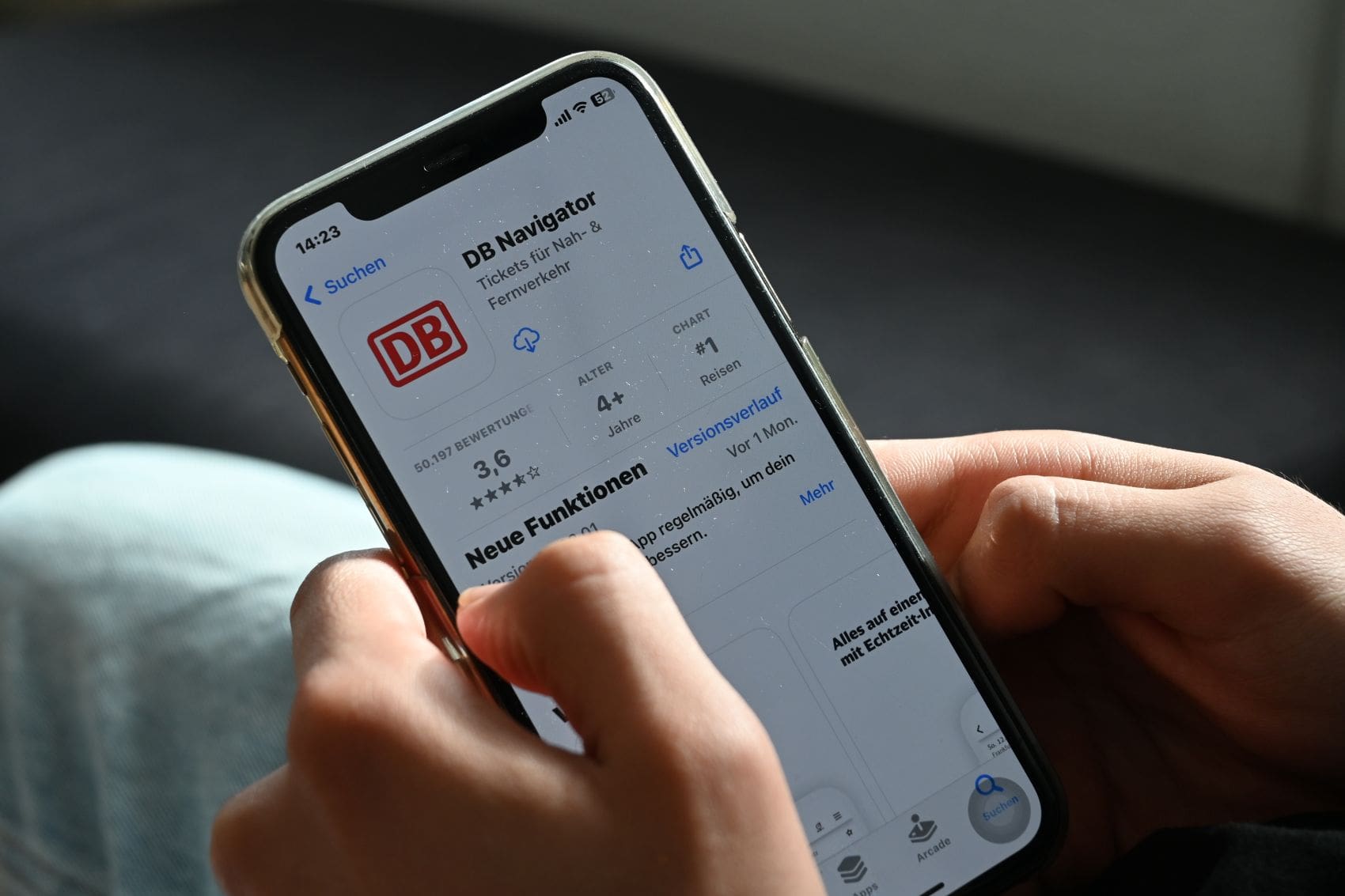 Eine Person hält ein Smartphone mit der App-Seite des DB Navigators in den Händen.