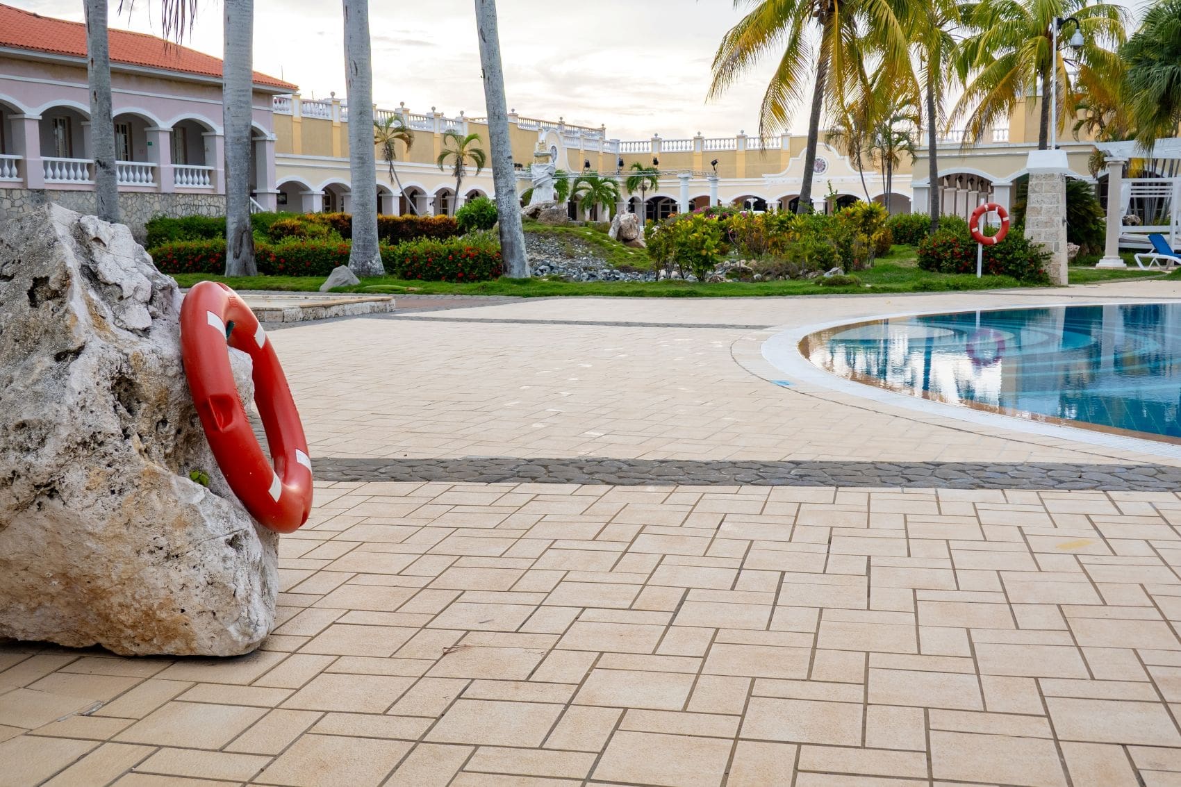 Menschenleerer Poolbereich eines Ferienhotels auf Kuba mit Palmen und Liegen.