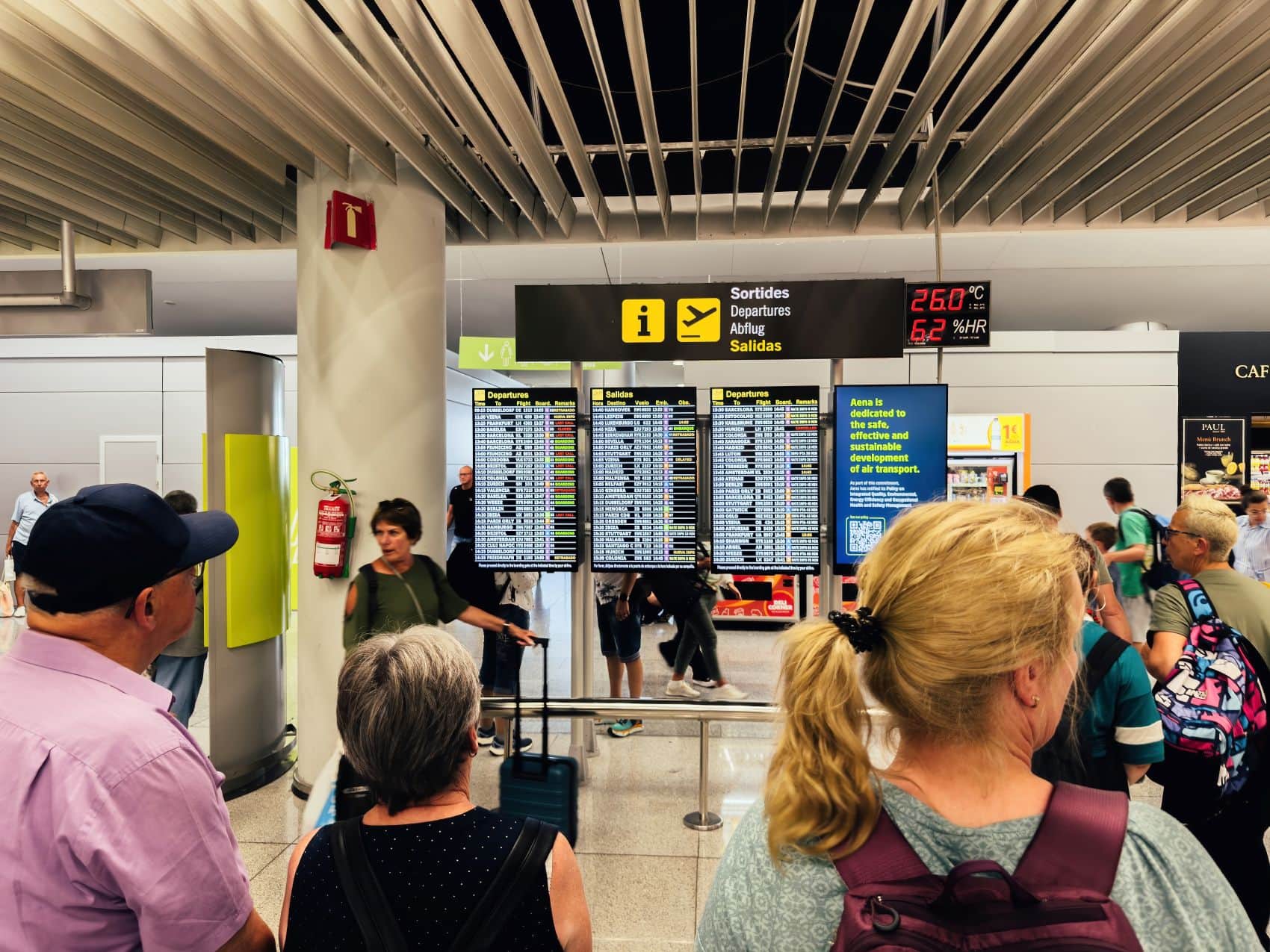 Reisende blicken im Terminal des Flughafens Palma de Mallorca auf die Anzeigetafel für Abflüge.