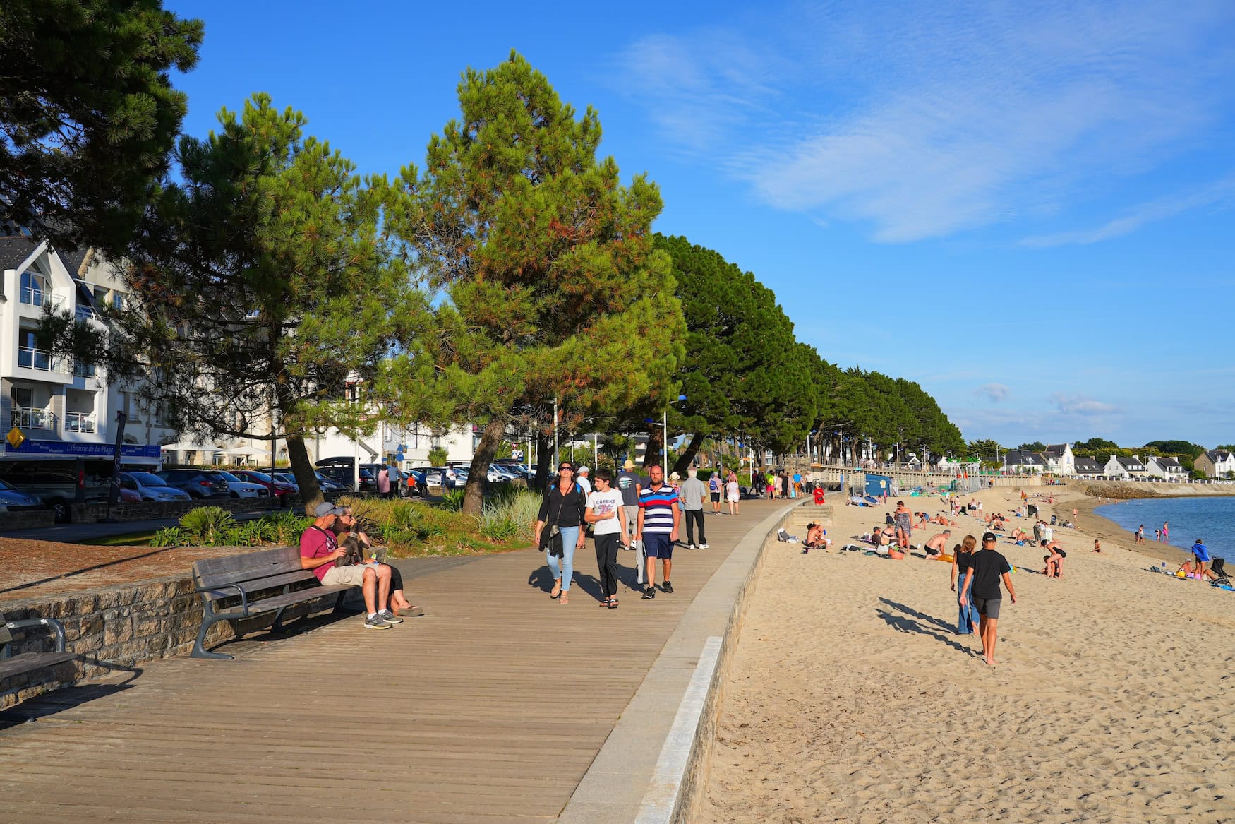 Strandpromenade von Bénodet mit Spaziergängern, Pinien und Strand im Sommer