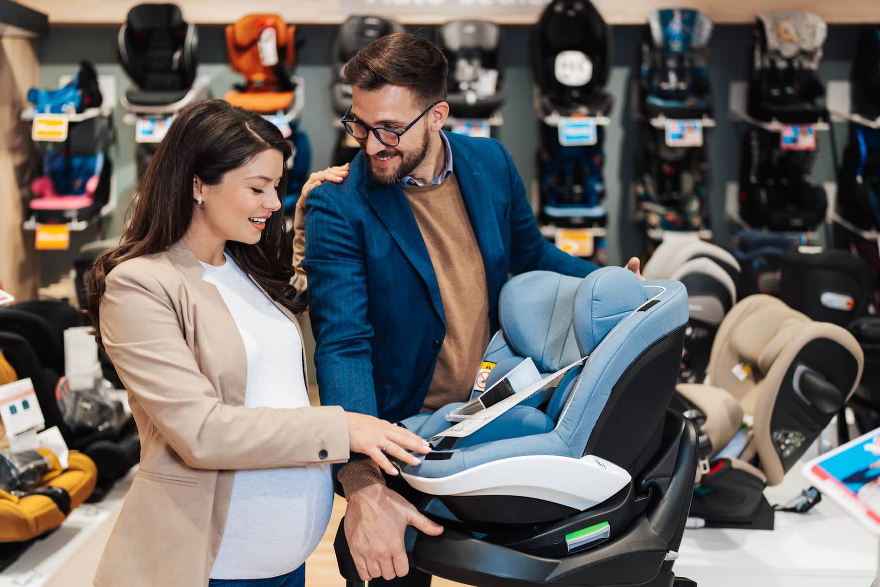Eltern prüfen einen Kindersitz im Fachgeschäft vor einer Regalwand mit Modellen