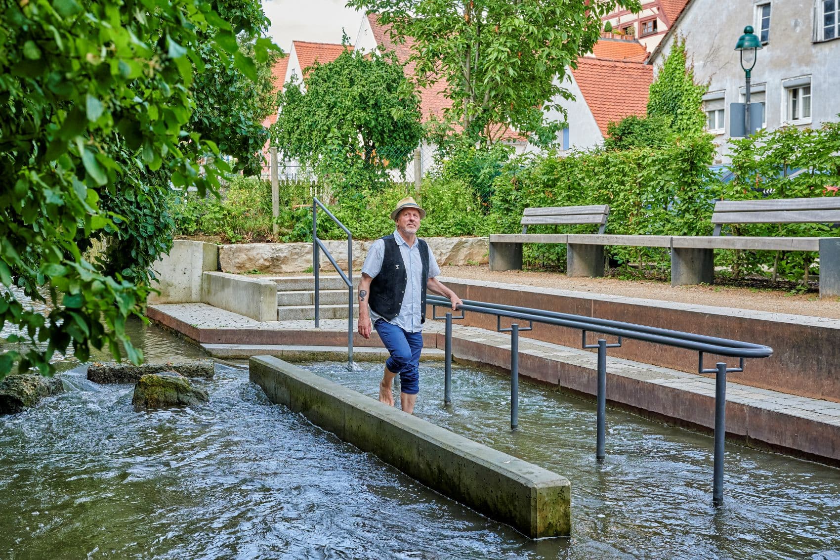 Ein Mann watet durch das Kneippbecken im Gerberviertel von Nördlingen und nutzt die Wasseranlage zum Wassertreten.