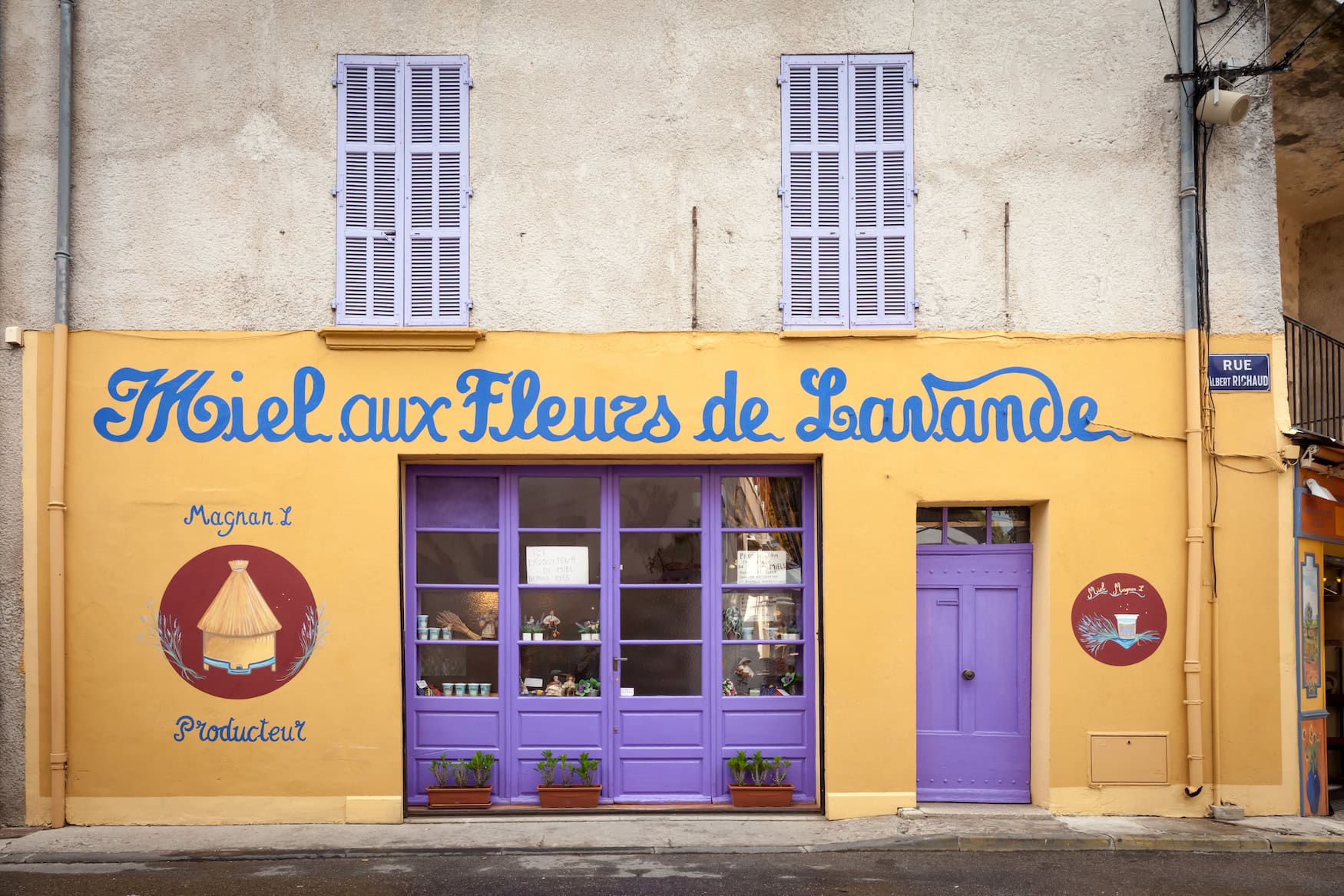 Bunte Ladenfassade eines Lavendelhonig-Produzenten in der Provence mit lila Fensterläden