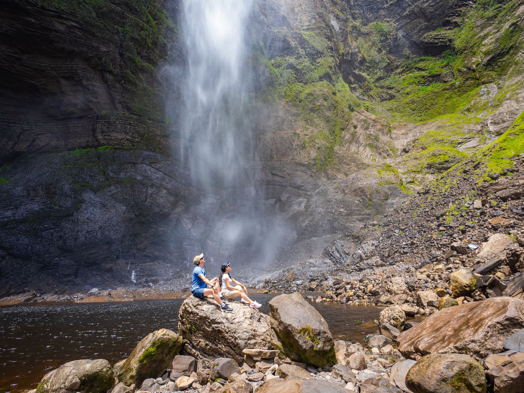 Der rund 770 Meter hohe Gocta-Wasserfall im Nebelwald der Region Amazonas mit zwei Personen auf einem Felsen