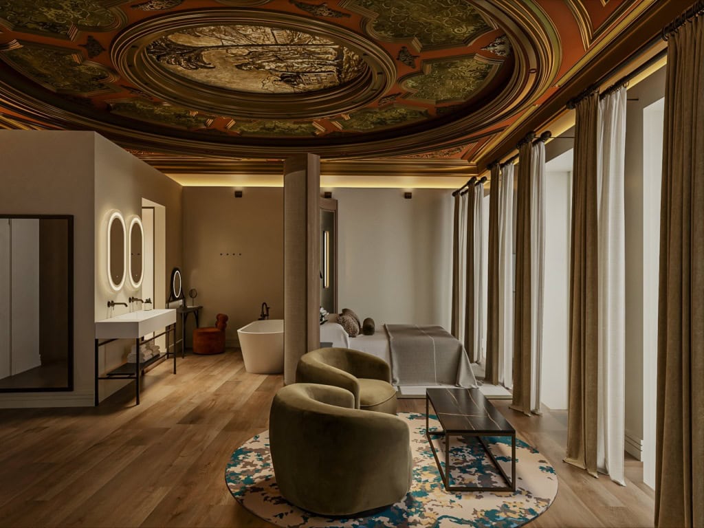 Rendering einer Suite mit reich verziertem, bemaltem Deckenrund in Gold- und Rottönen, einem Doppelbett vor olivgrüner Wand und einer Sitzecke mit zwei Sesseln auf rundem Teppich.