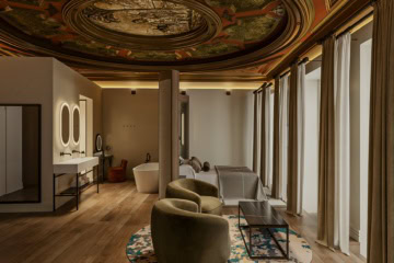 Rendering einer Suite mit reich verziertem, bemaltem Deckenrund in Gold- und Rottönen, einem Doppelbett vor olivgrüner Wand und einer Sitzecke mit zwei Sesseln auf rundem Teppich.
