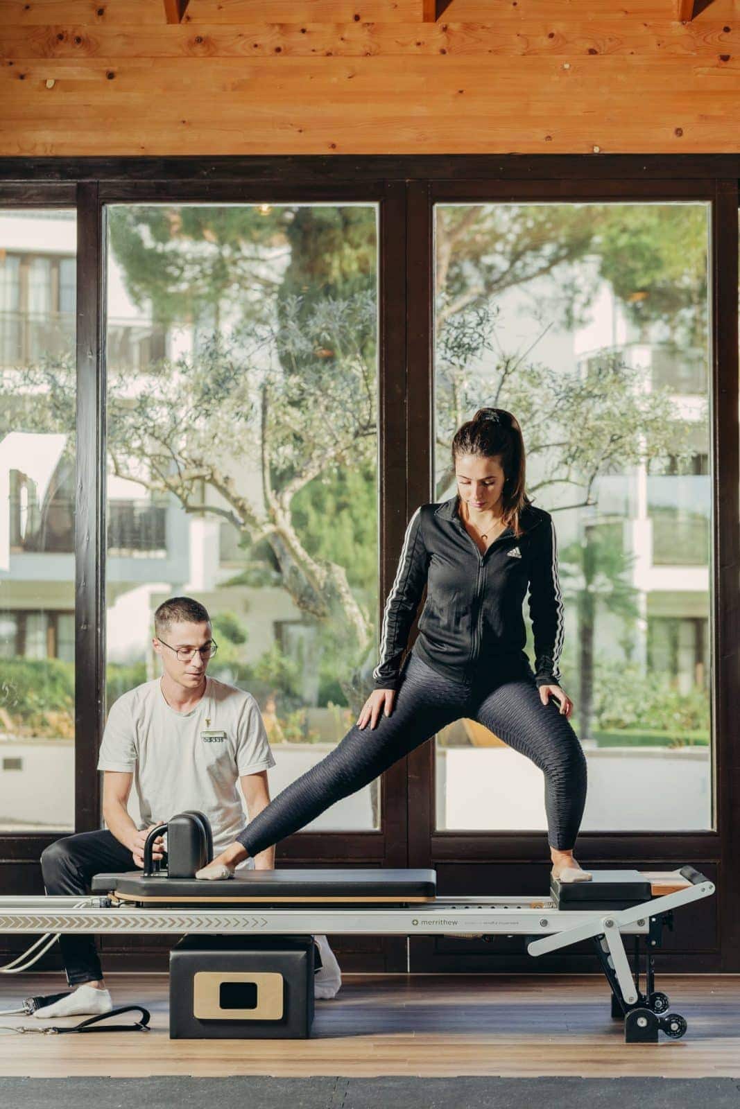 Reformer-Pilates mit persönlicher Betreuung im Pine Cliffs Resort an der Algarve, dahinter Fensterfront mit Blick in den Pinienpark.