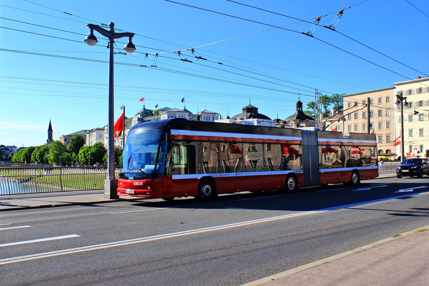 Ein roter Bus fährt über eine Brücke in Salzburg