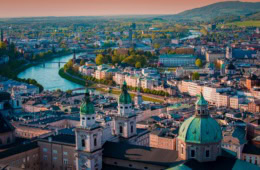 Luftaufnahme der Stadt Salzburg in Österreich im Abendlicht, mittig von der Salzach durchkreuzt