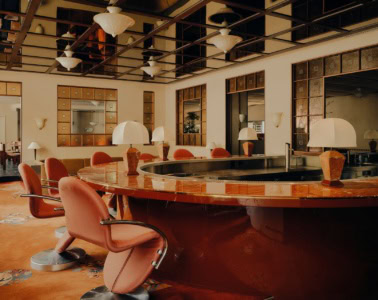 Design-Bar im The Dean Munich mit geschwungener Marmortheke, rosafarbenen Sesseln und stilvollem Interieur im Münchner Westend.
