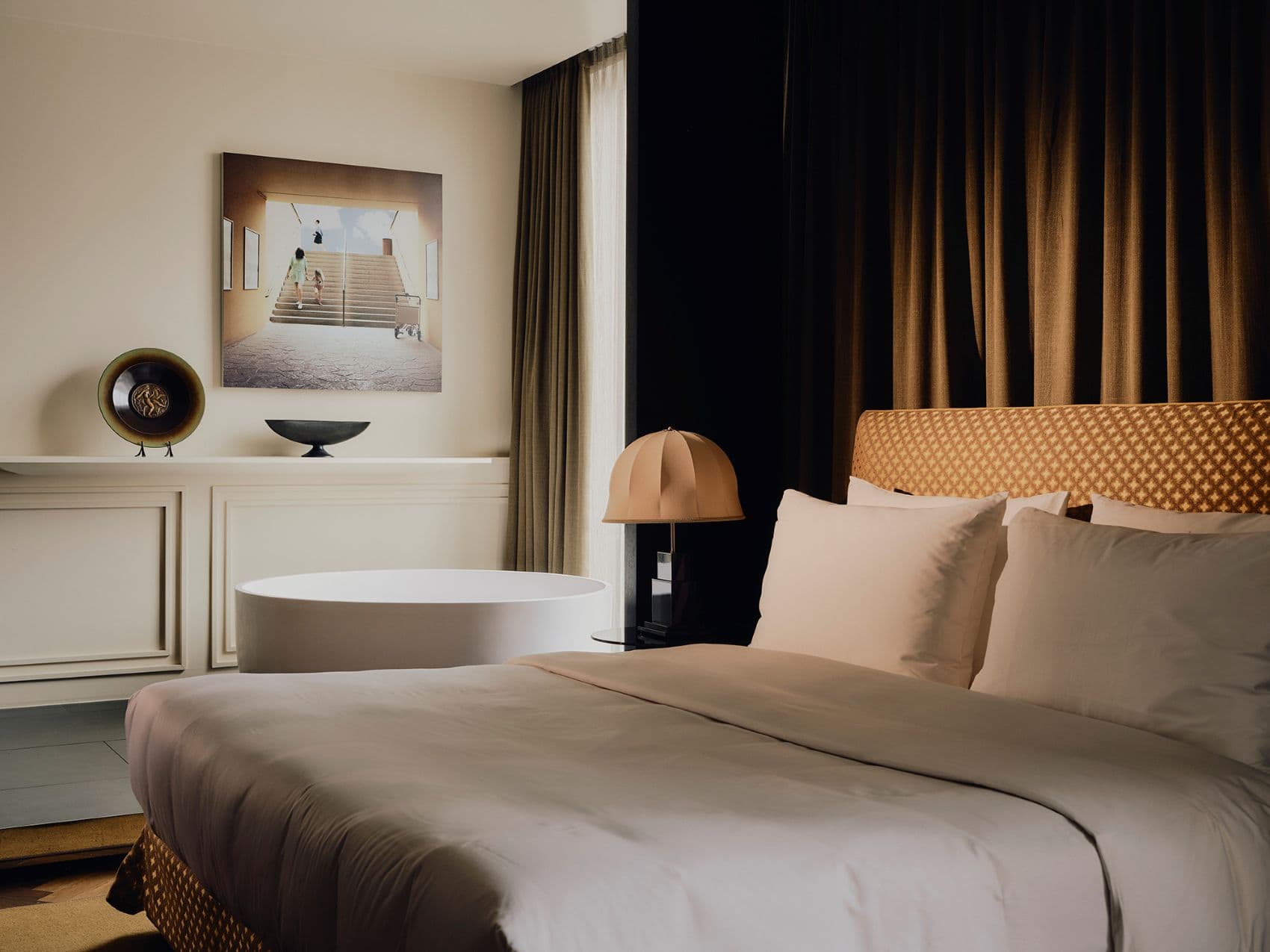 Modernes Gästezimmer im The Dean Munich mit großem Doppelbett, freistehender Badewanne und elegantem Design im Stil von Jugendstil und 1980er-Jahren.