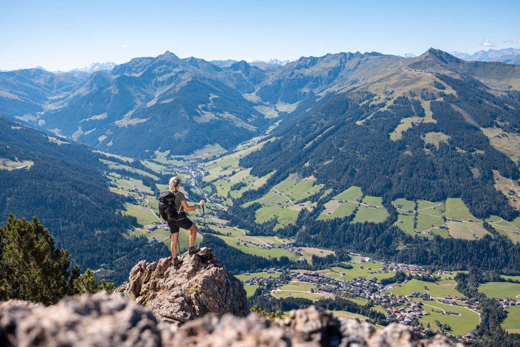 Eine Wanderin genießt den Ausblick von einem Gipfel über das Alpbachtal und die Tiroler Alpen.