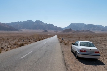 Auto auf einer einsamen Straße in einer Wüstenlandschaft