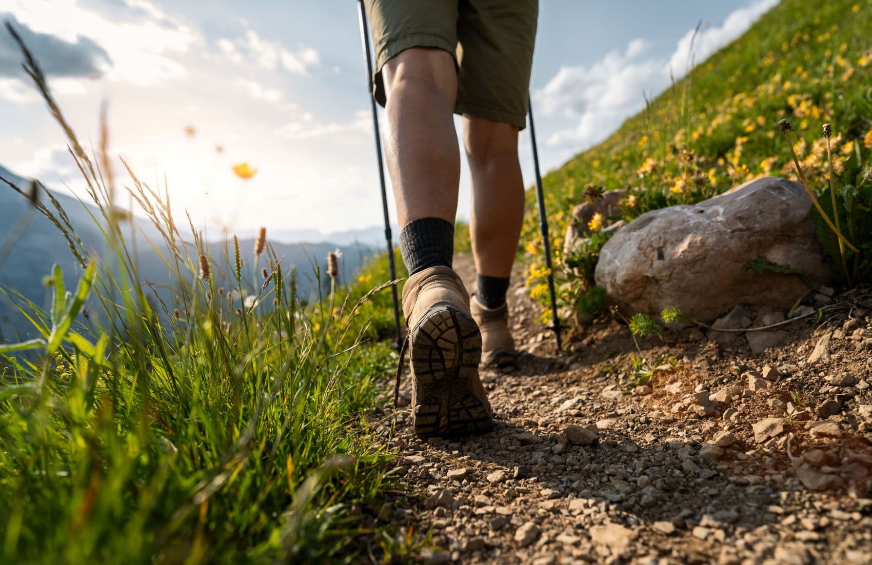 Wanderer mit Wanderschuhen und Stöcken auf einem Bergweg