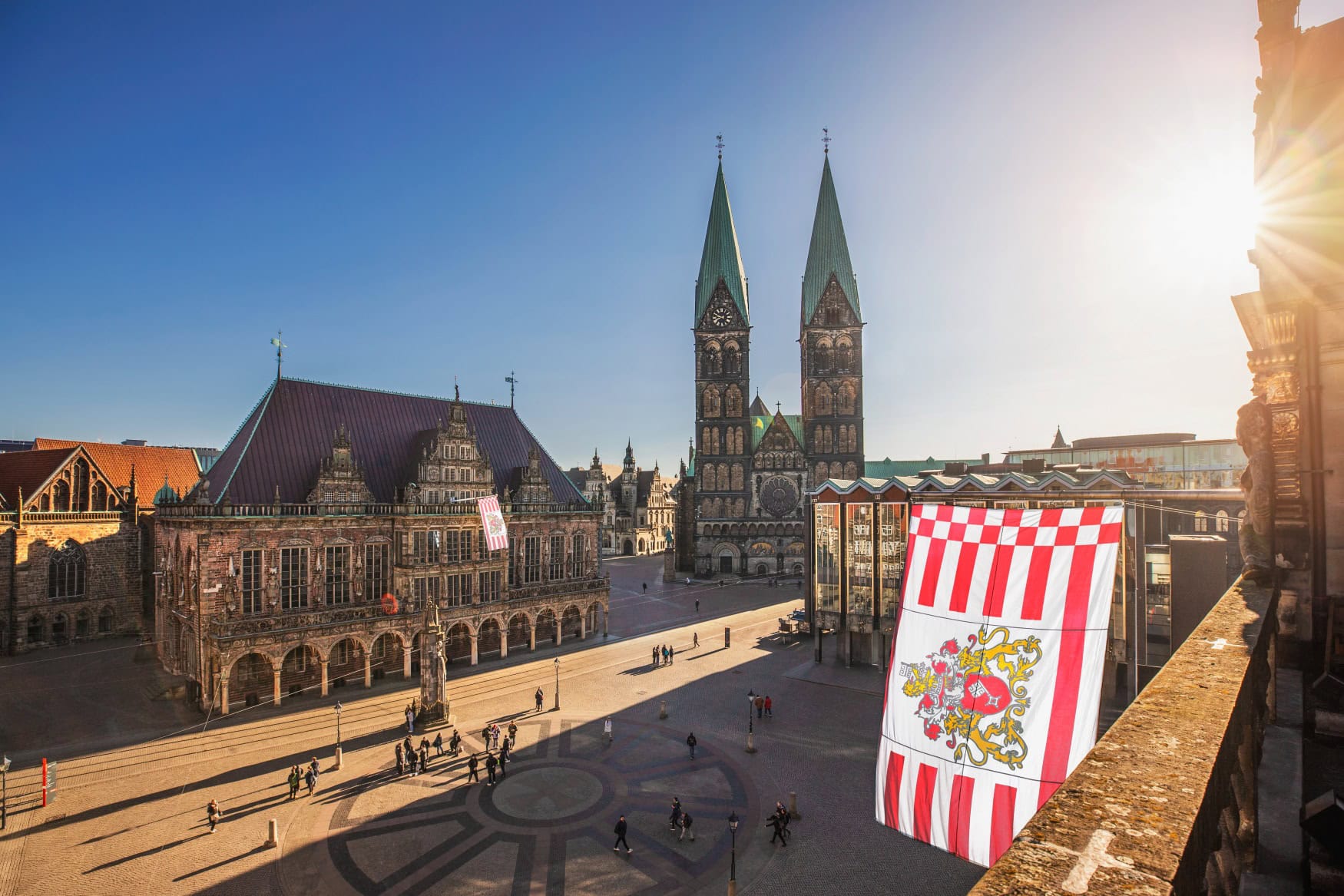 Blick von einem Balkon auf den sonnenbeschienenen Bremer Marktplatz, im Hintergrund der Dom