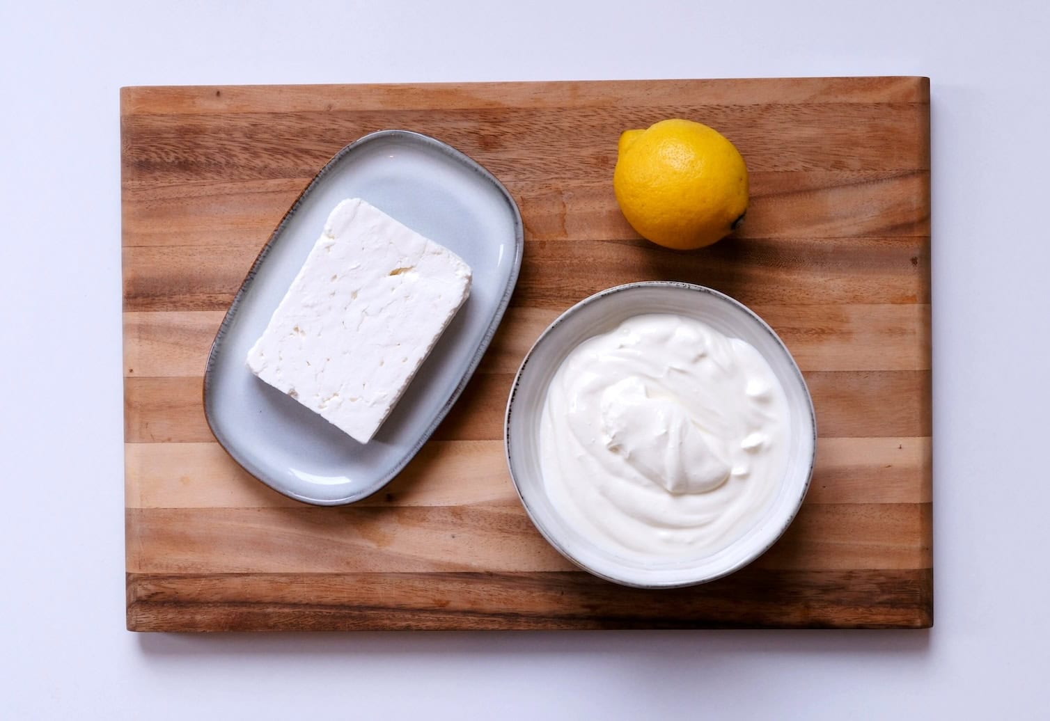Feta, Zitrone und Joghurt auf einem Holzbrett.