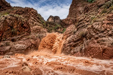 Schlammige Wassermassen rauschen durch einen felsigen Canyon