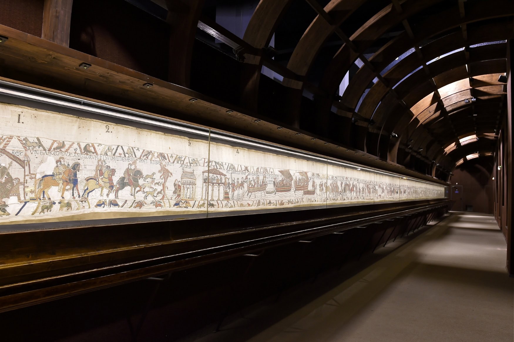 Aufnahme des Teppichs von Bayeux in seiner Vitrine. Durch die Aufnahme wird sichtbar, wie lang der Teppich ist