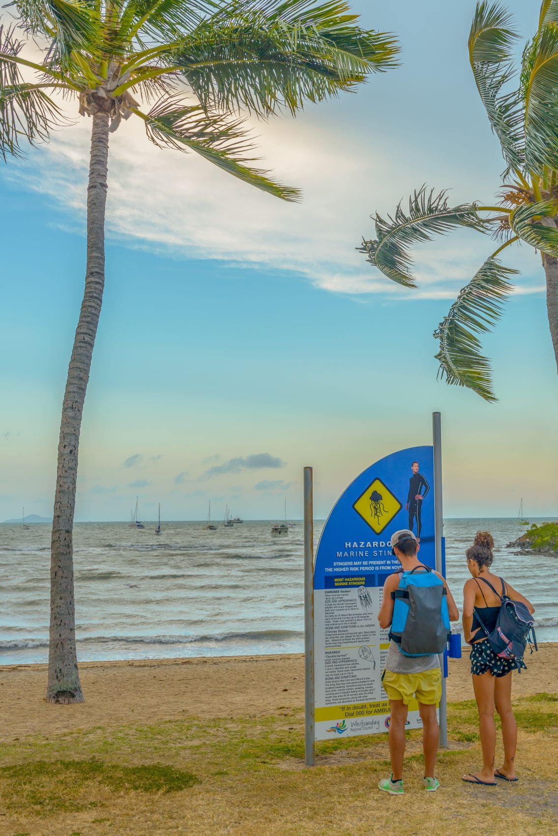 Urlauber vor Seewesen-Warnhinweisschild in Airlie Beach, Australien