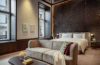 Suite im Almanac Vienna; ein hohes Zimmer mit einem breiten Doppelbett, davor ein Polstersofa