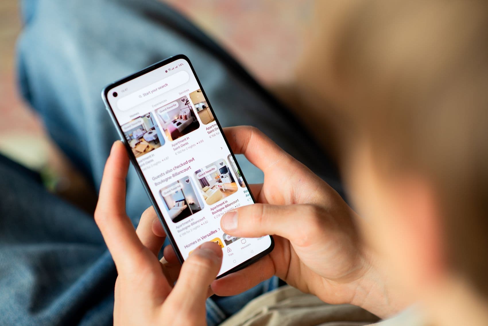 Eine Reisende sucht auf dem Smartphone nach Ferienwohnungen auf Airbnb.