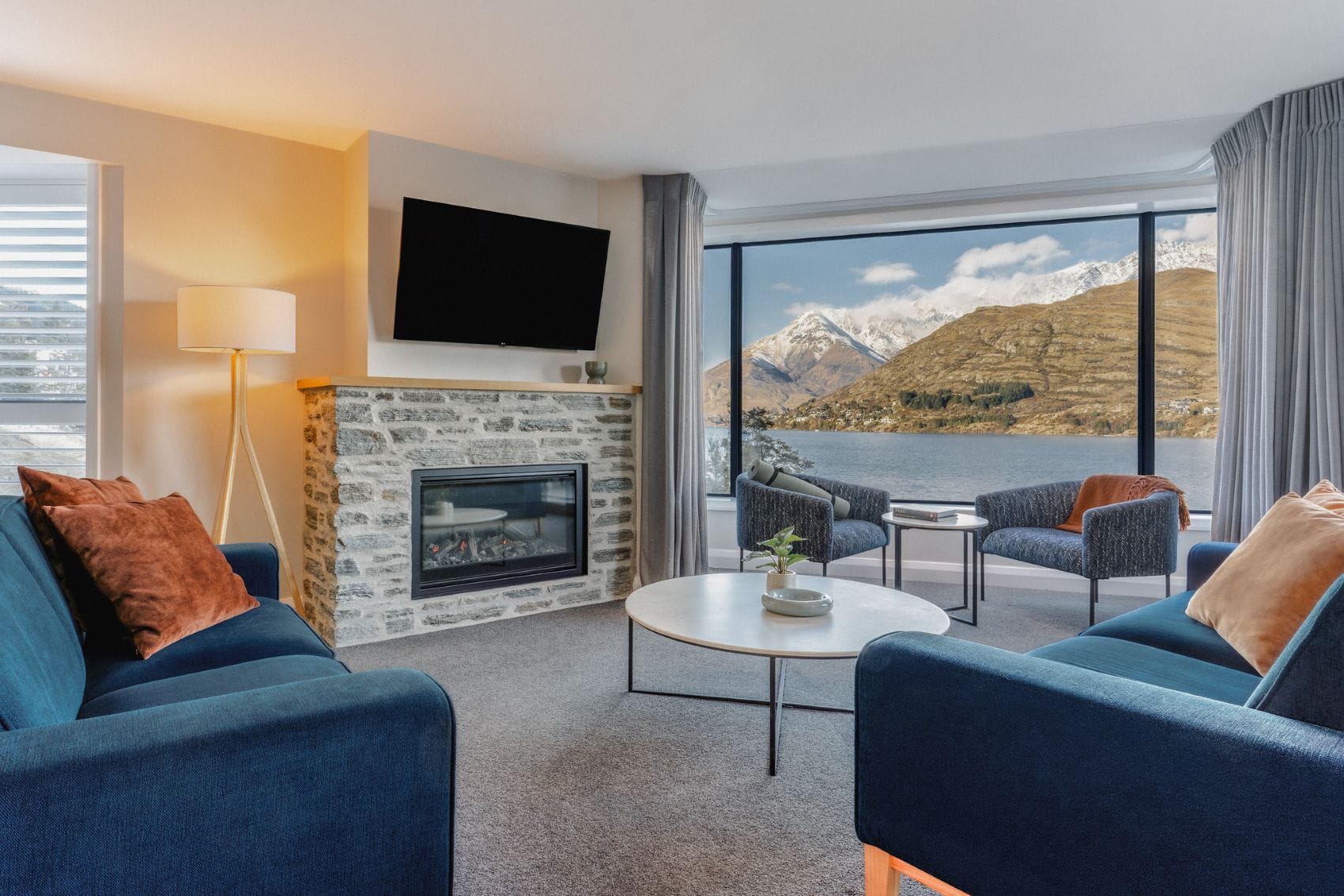 Wohnbereich im Avani Queenstown mit Kamin und Blick auf den Lake Wakatipu und die Berge
