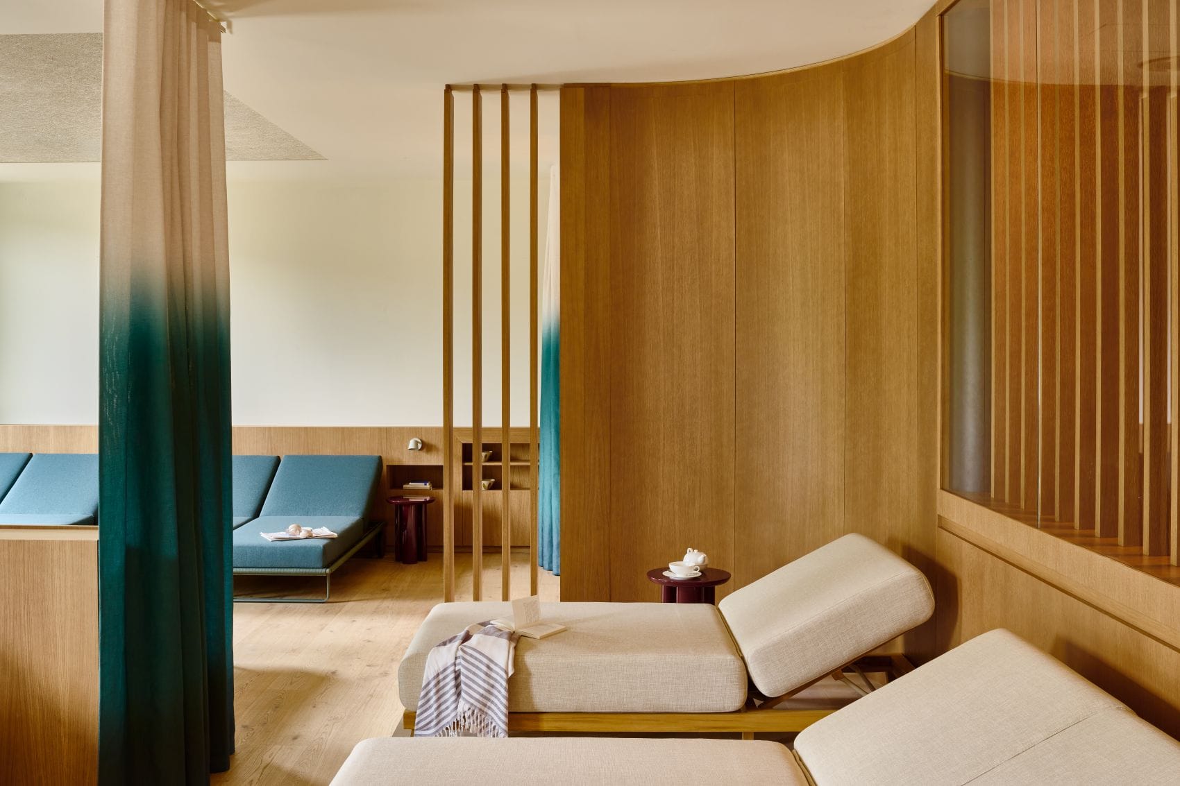 Ruheraum im Acquapura Spa des Falkensteiner Resort Lake Garda mit Liegen, Holzelementen und petrolfarbenen Vorhängen.