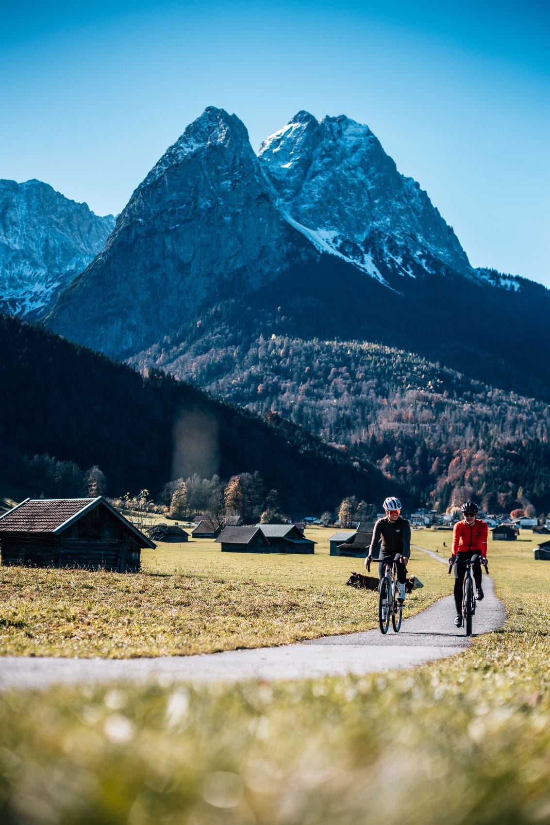 Zwei Gravelbiker fahren vor einer imposanten Bergkulisse durch die Zugspitz Region.