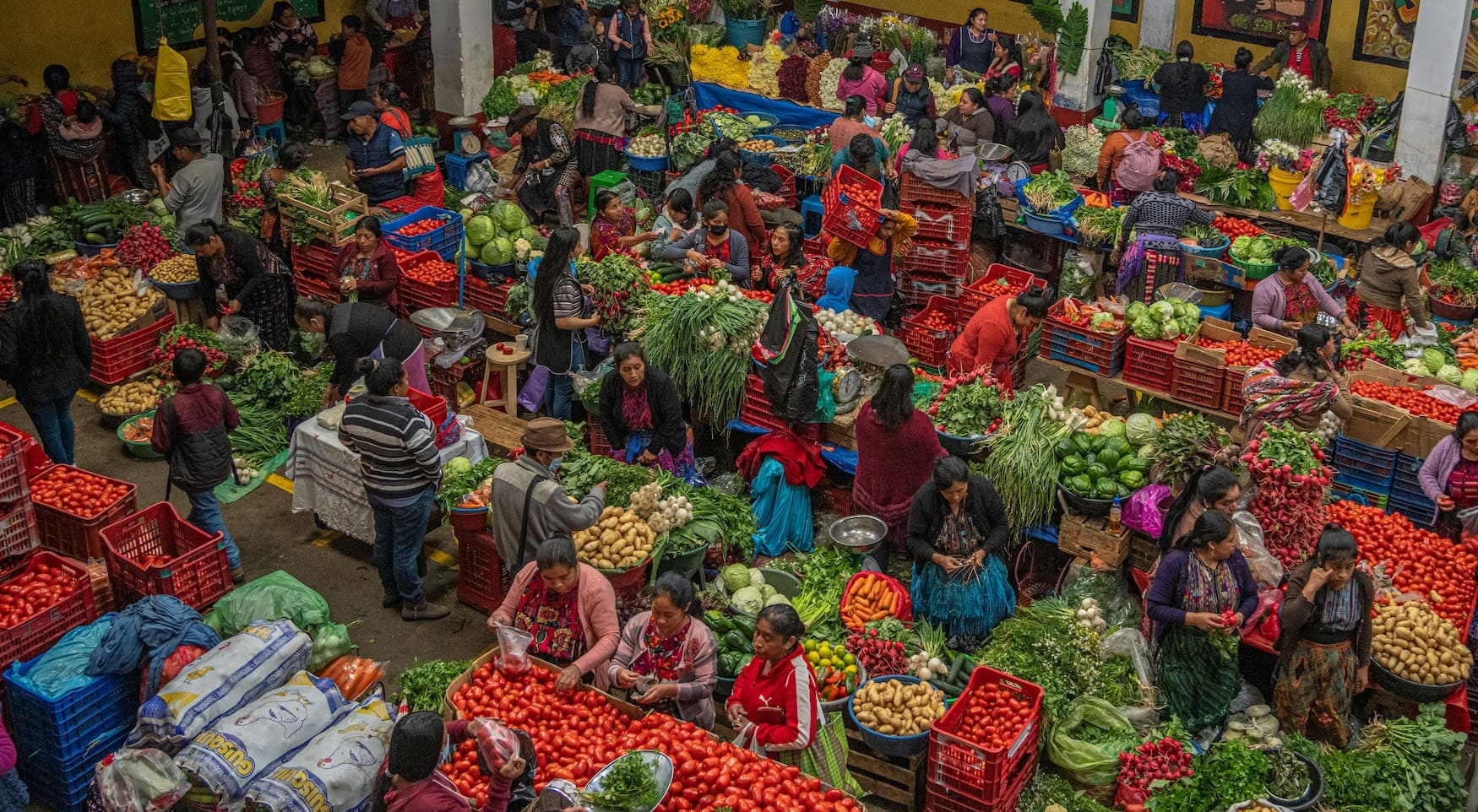 Blick über einen belebten Maya-Markt im guatemaltekischen Hochland mit Ständen voller Gemüse.