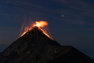 Der Vulkan Fuego in Guatemala schleudert bei Nacht glühende Lava in den Sternenhimmel.