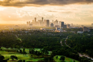 Skyline von Houston im Abendlicht mit weitläufigen Grünflächen im Vordergrund