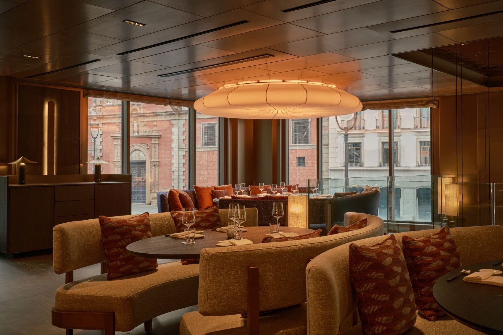 Restaurant im Nobu Hotel Madrid mit warmen Holztönen, bodentiefen Fenstern und Blick auf die historische Architektur der Stadt.