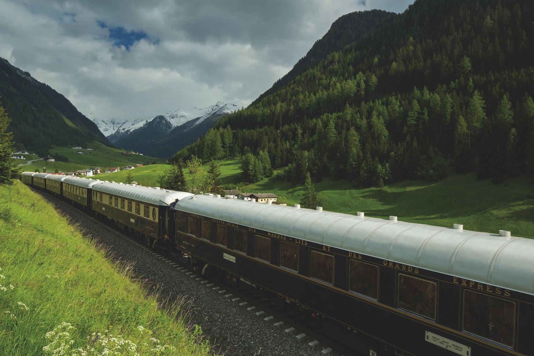 Der Venice Simplon-Orient-Express mit dunkelblauen Wagen der Compagnie Internationale des Wagons-Lits auf der Fahrt durch ein Alpental