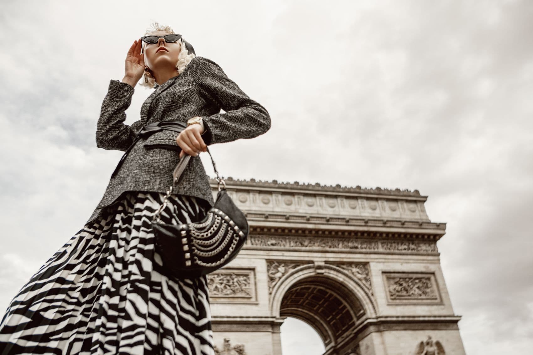 Frau in elegantem Outfit vor dem Arc de Triomphe in Paris