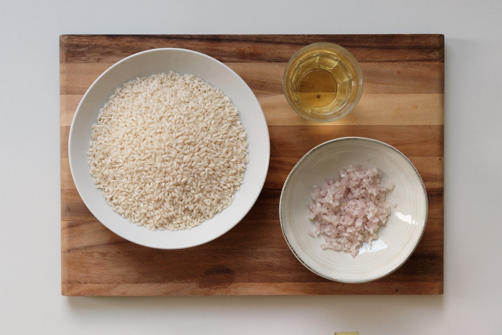 Ein Holzbrett mit Risottoreis, Zwiebeln und Weißwein.