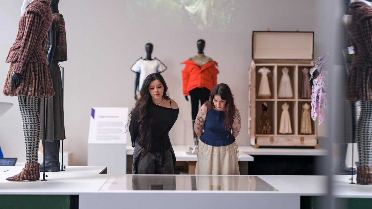 Zwei Frauen schauen sich die Ausstellung Catwalk näher an.